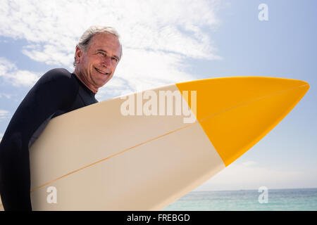 Portrait of senior man in wetsuit holding a surfboard Banque D'Images