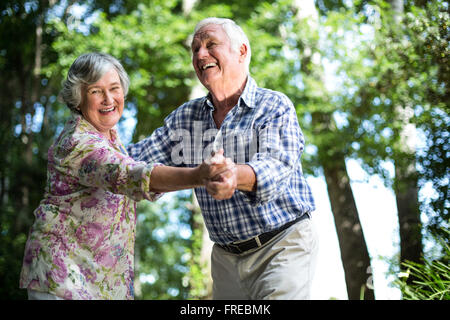 Happy senior woman dancing avec mari contre des arbres Banque D'Images