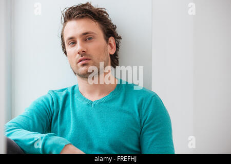 Portrait de beau jeune homme détendu en bleu sur fond blanc Banque D'Images