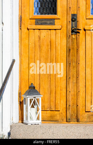 Une lanterne blanc se tiennent à l'extérieur l'entrée d'une maison. Une partie de la porte visible jusqu'à la poignée de la boîte aux lettres de. Banque D'Images