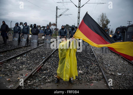 Un garçon est titulaire d'un drapeau allemand et montre en face de la police ; les réfugiés et migrants échoués protester contre la frontière de la Macédoine grecque, exigeant pour les frontières d'ouvrir, afin de continuer leur voyage vers le nord de l'Europe du nord, près du village grec de Idomeni Banque D'Images