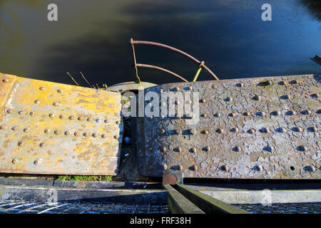 Grunge metal industriel à fond vers le bas d'un vieux pont de fer corrodées avec rivets sur l'eau. Banque D'Images