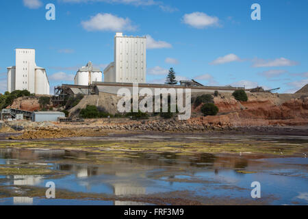 Blanc petit silo de stockage accessible sur le dessus de la mer avec des reflets dans l'eau peu profonde avec de la boue et d'algues Banque D'Images