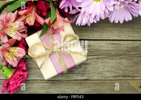 Boîte cadeau rustique avec coin border de fleurs sur fond de bois Banque D'Images