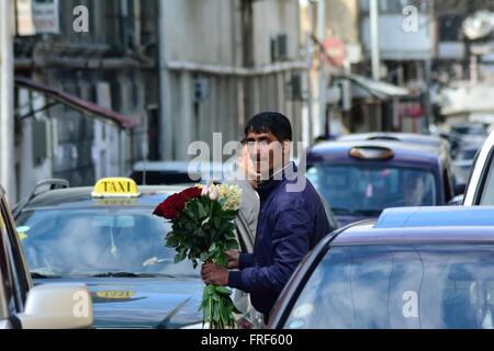 BAKU, Azerbaïdjan - 19 mars 2014 un jeune homme propose des pilotes l'occasion d'acheter des fleurs qu'ils se déplacer lentement sur le trafic lourd Banque D'Images