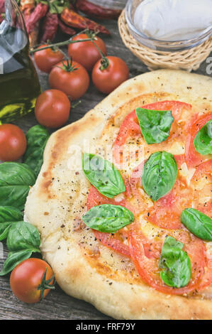 Les tomates fraîches et de feuilles de basilic pizza Banque D'Images