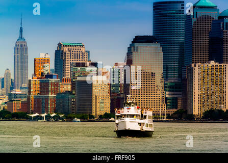 Lower Manhattan skyline et statue Cruises bateau dans la région de Bay, New York, USA. Banque D'Images