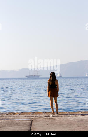 Une jeune fille debout sur le port de Santorini Banque D'Images