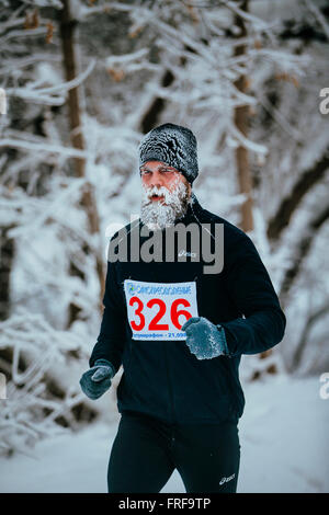 Jeune homme jogger qui traverse un parc enneigé alley. face au gel et la barbe au cours de l'hiver de Tchéliabinsk marathon Banque D'Images