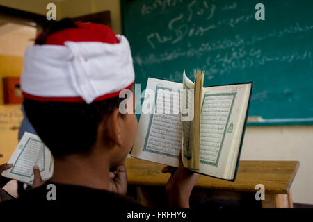 Un écolier récite des versets du Coran en arabe dans une salle de classe de l'Organisation islamique al-Koom Bourit Institute pour les garçons dans le village de Qom (Koom), sur la rive ouest de Louxor, vallée du Nil, en Égypte. Banque D'Images