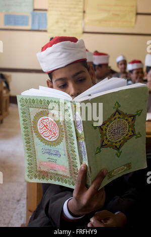 Un écolier récite des versets du Coran en arabe dans une salle de classe de l'Organisation islamique al-Koom Bourit Institute pour les garçons dans le village de Qom (Koom), sur la rive ouest de Louxor, vallée du Nil, en Égypte. Banque D'Images