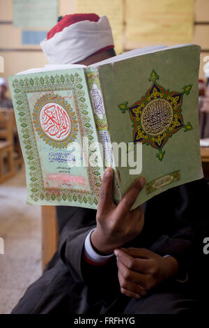 Un écolier récite des versets du Coran en arabe dans une salle de classe de l'Organisation islamique al-Koom Bourit Institute pour les garçons dans le village de Qom (Koom), sur la rive ouest de Louxor, vallée du Nil, en Égypte. Banque D'Images