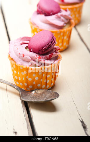 Rose Crème fraîche berry cupcake macaron avec sur le dessus sur table en bois rustique Banque D'Images