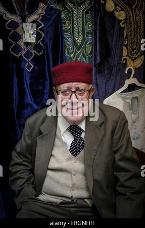 Moitié du corps, PORTRAIT D'UN VIEIL HOMME TUNISIEN VENDEUR portant des vêtements traditionnels EN FACE DE VÊTEMENTS TRADITIONNELS QU'IL VEND, Tuni Banque D'Images