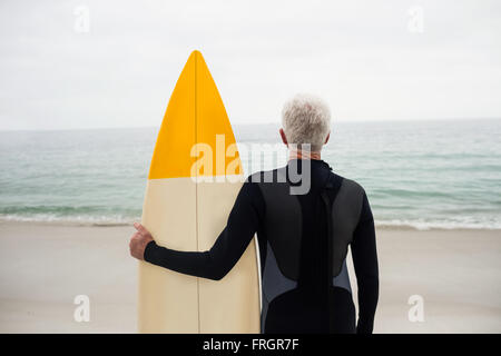 Vue arrière du man wetsuit holding un surf Banque D'Images