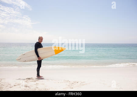 Portrait of senior man in wetsuit holding a surfboard Banque D'Images