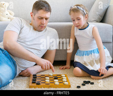 Petite fille et son père jouer aux dames. Banque D'Images