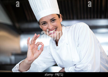 Happy female chef showing ok sign in kitchen Banque D'Images