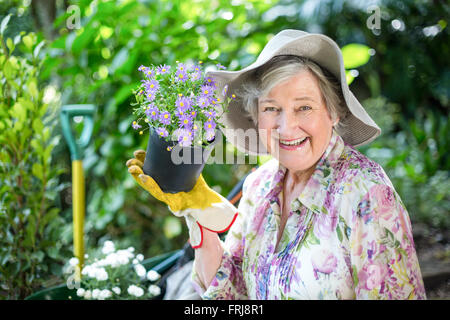 Portrait of senior woman with potted plant in garden Banque D'Images