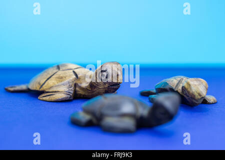 Tortue en bois figurines sur fond bleu Banque D'Images