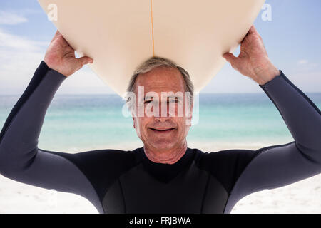 Portrait of senior man holding a surfboard sur sa tête Banque D'Images