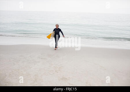 Hauts femme marche sur la plage avec un surf Banque D'Images