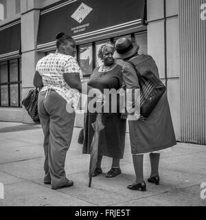 Photo candide de trois femmes afro-américaines bavardant dans la rue à New York, USA. Banque D'Images