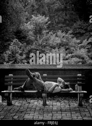 Man sleeping on bench en dehors de Central Park, New York City, USA Banque D'Images