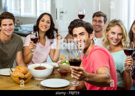 Portrait of happy friends holding wine glasses at table Banque D'Images