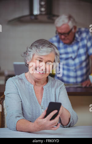 Senior woman using phone in kitchen Banque D'Images