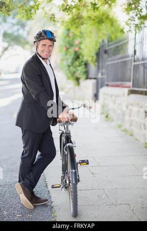 Portrait of happy businessman standing with bicycle Banque D'Images