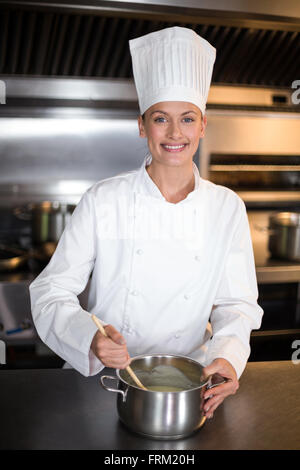 Portrait of smiling female chef cooking in kitchen Banque D'Images