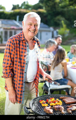 Portrait of senior man preparing food sur barbecue Banque D'Images