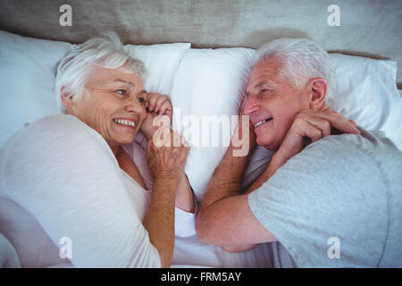 Heureux couple tandis que lying on bed Banque D'Images