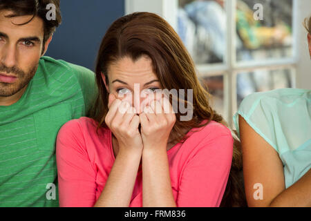 Femme anxieuse à regarder la télévision avec des amis Banque D'Images