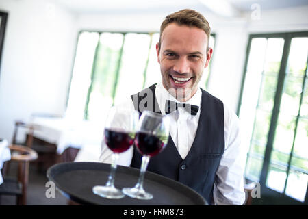 Waiter holding tray with red wine Banque D'Images