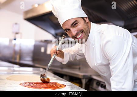 Pizza chef mettre la sauce sur la base Banque D'Images