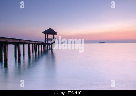 Belle Lumière du matin, de l'atterrissage en bois avec pavillon dans la mer à plage de sable noir, province de Rayong, Thaïlande. Banque D'Images