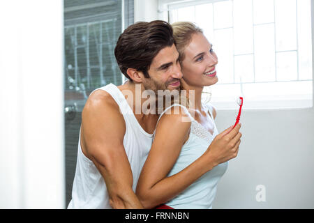 Couple hugging tandis que se brosser les dents Banque D'Images