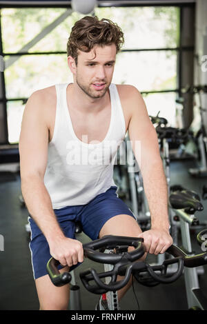 Man working out on exercise bike at spinning class Banque D'Images