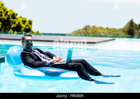 Businessman using laptop on inflatable Banque D'Images