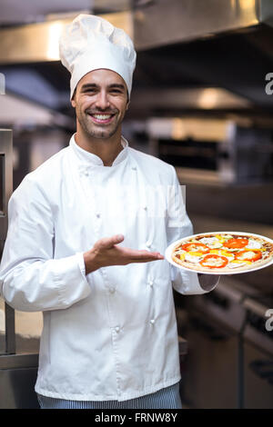 Beau chef presenting pizza Banque D'Images