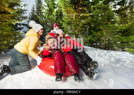 Groupe d'enfants équitation en bas de la colline sur red ice-boat Banque D'Images