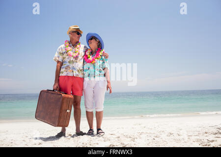 Happy senior couple holding suitcase sur la plage Banque D'Images