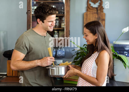 Happy young couple cooking food in kitchen Banque D'Images