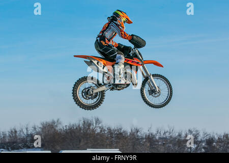 Moto Racer haut vol sur fond de ciel bleu au cours de l'hiver la Coupe du motocross Banque D'Images