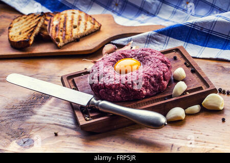 Le boeuf cru savoureux .Steak tartare. Steak tartare classique sur planche de bois. Ingrédients : viande de boeuf sel poivre piment ail oeuf Banque D'Images