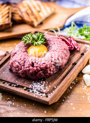 Le boeuf cru savoureux .Steak tartare. Steak tartare classique sur planche de bois. Ingrédients : viande de boeuf sel poivre piment ail oeuf Banque D'Images