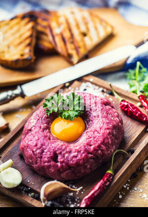 Le boeuf cru savoureux .Steak tartare. Steak tartare classique sur planche de bois. Ingrédients : viande de boeuf sel poivre piment ail oeuf Banque D'Images