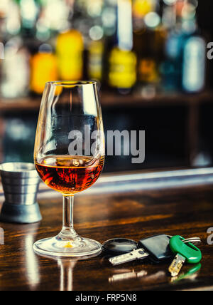 L'alcoolisme. Tasse cognac ou brandy hand man les clés de la voiture et chauffeur irresponsable. Banque D'Images